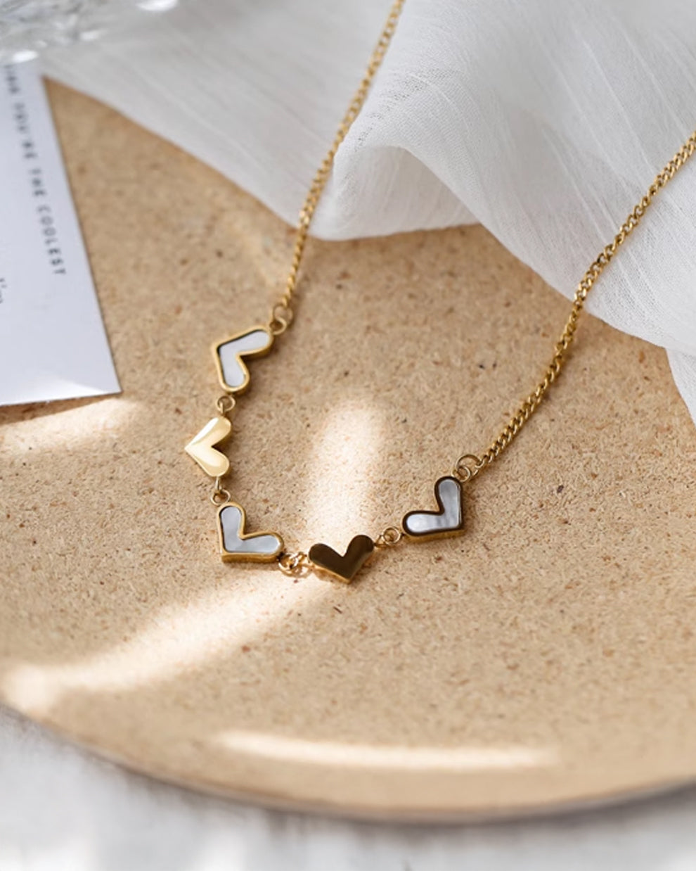 a necklace with two hearts on it sitting on a plate