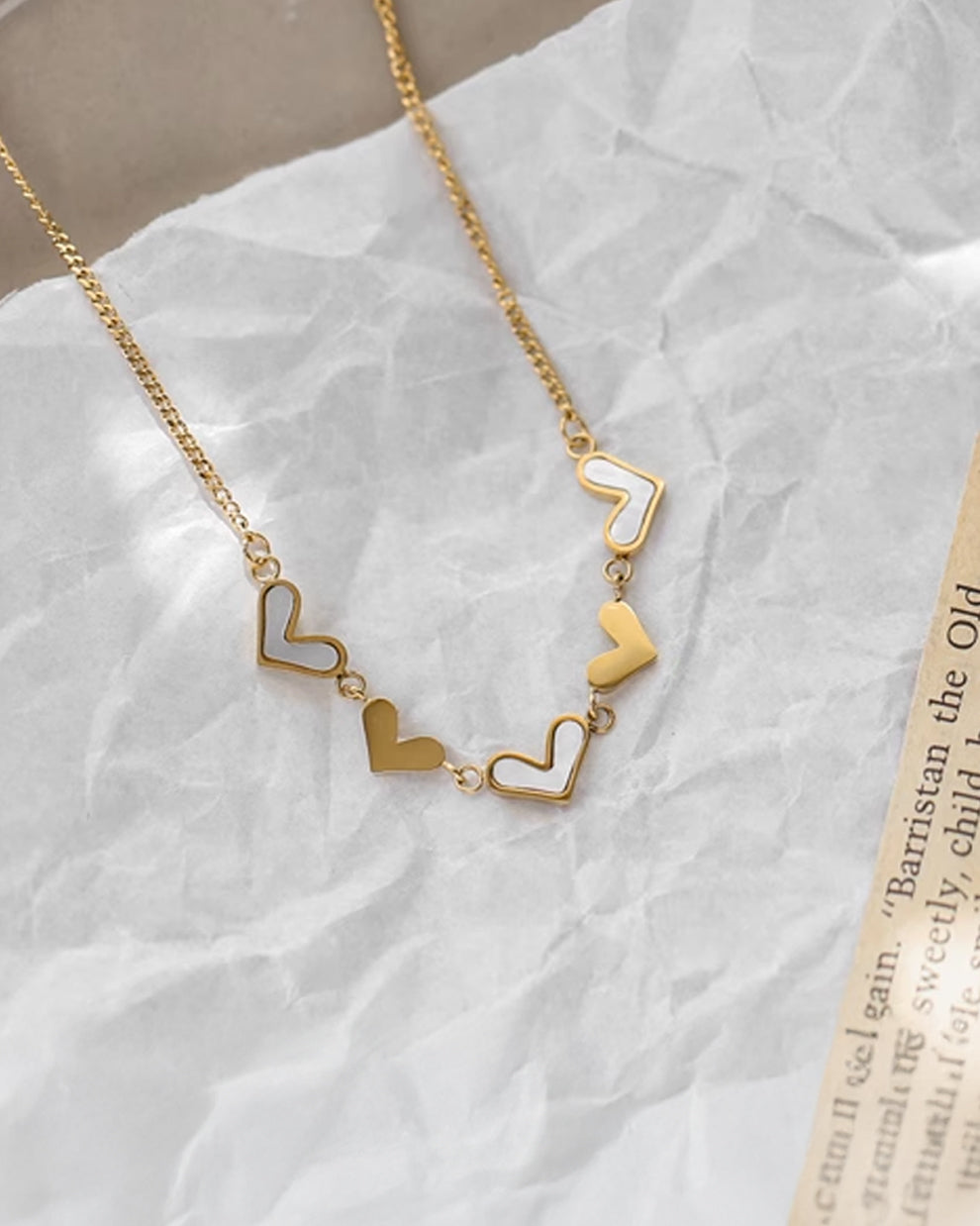 a necklace with a heart on it sitting on top of a piece of paper