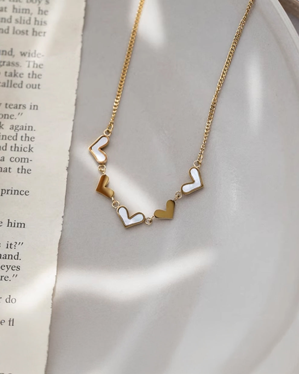 a gold necklace with two hearts on it