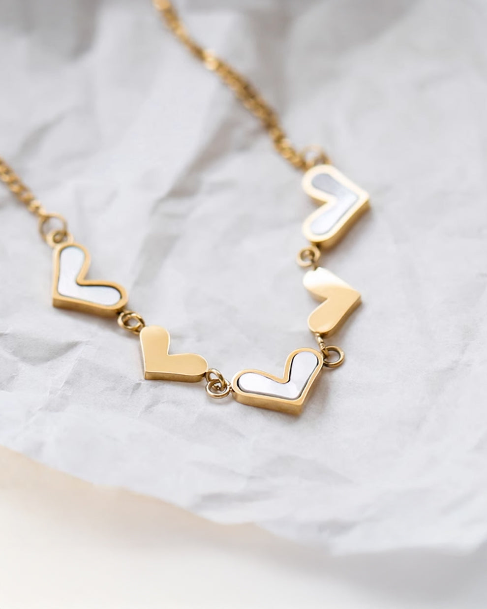 a gold and white necklace on a white piece of paper